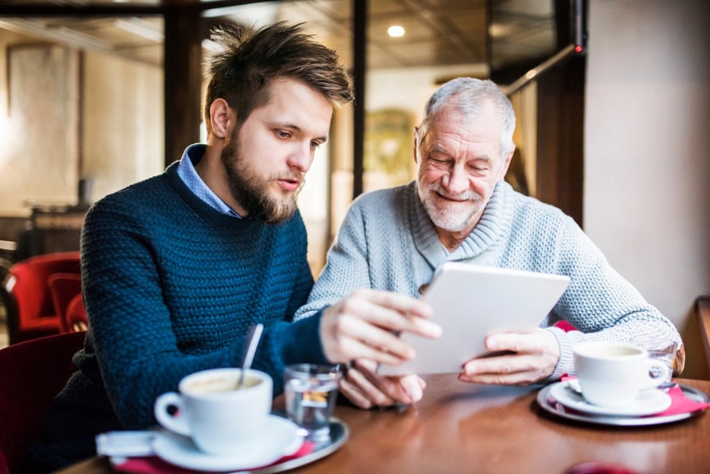 Renovering av bostadsrätt. En yngre man sitter och samtalar med en betydligt äldre gråhårig man. De håller i ett dokument som de bägge leende intresserat läser.